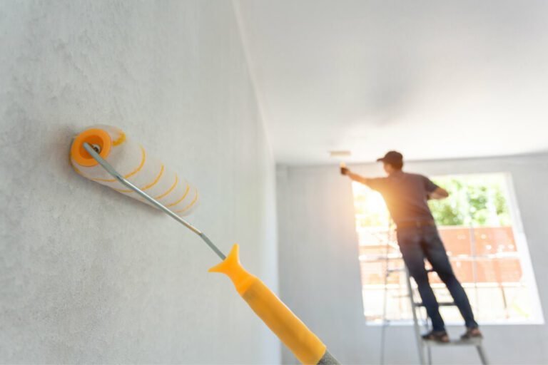 A worker with a roller painting the interior background.